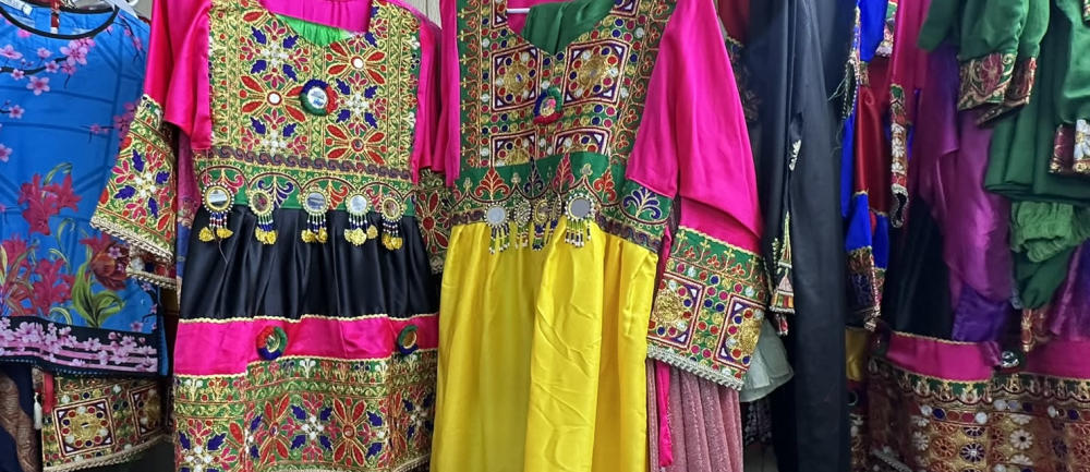 Close up of brightly colored traditional Afghan dresses with brocade and other ornamentation.